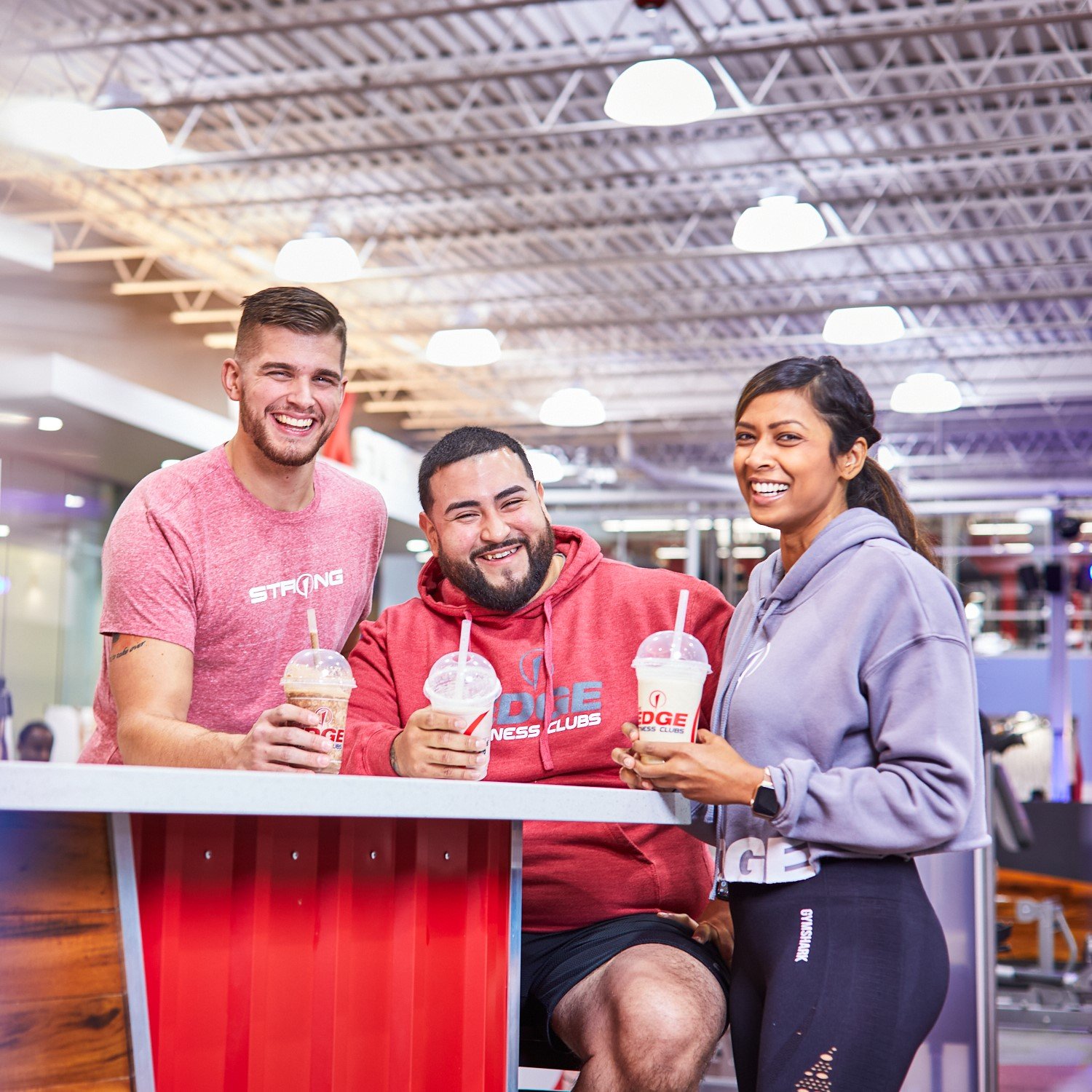Three people smiling drinking shakes at the shake bar.